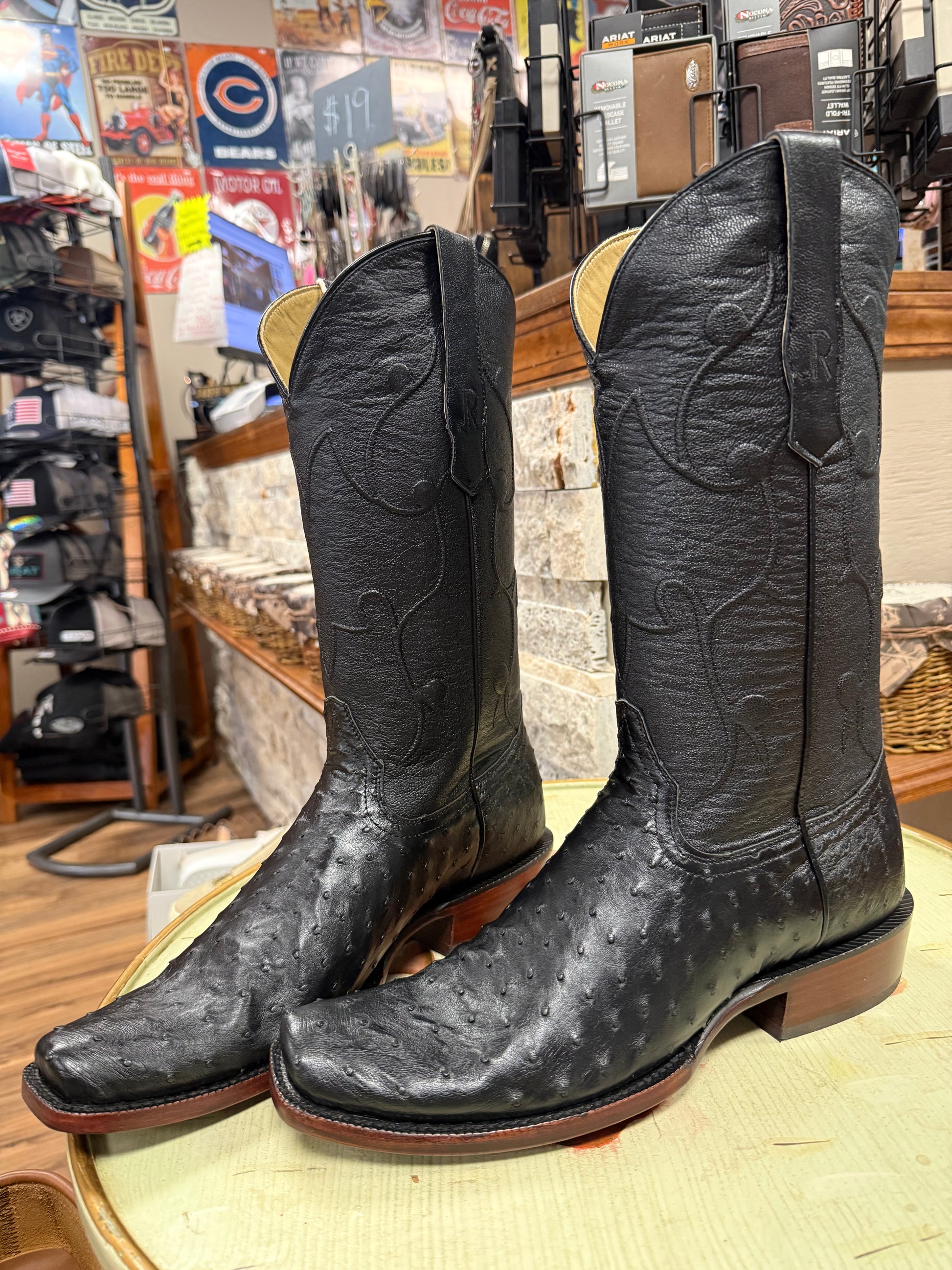 Black cowboy boots on a wooden surface with a store interior background