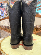 Pair of black cowboy boots on a round surface with a store interior background