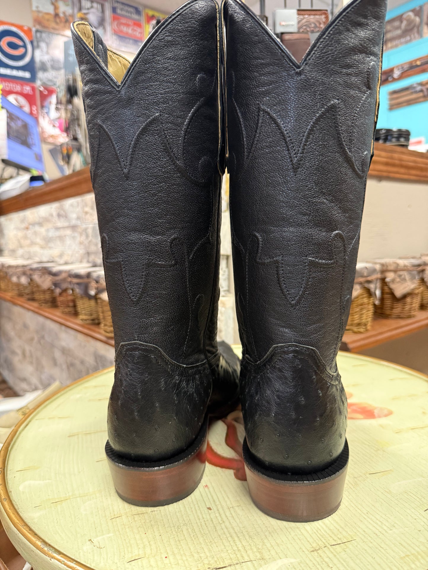 Pair of black cowboy boots on a round surface with a store interior background