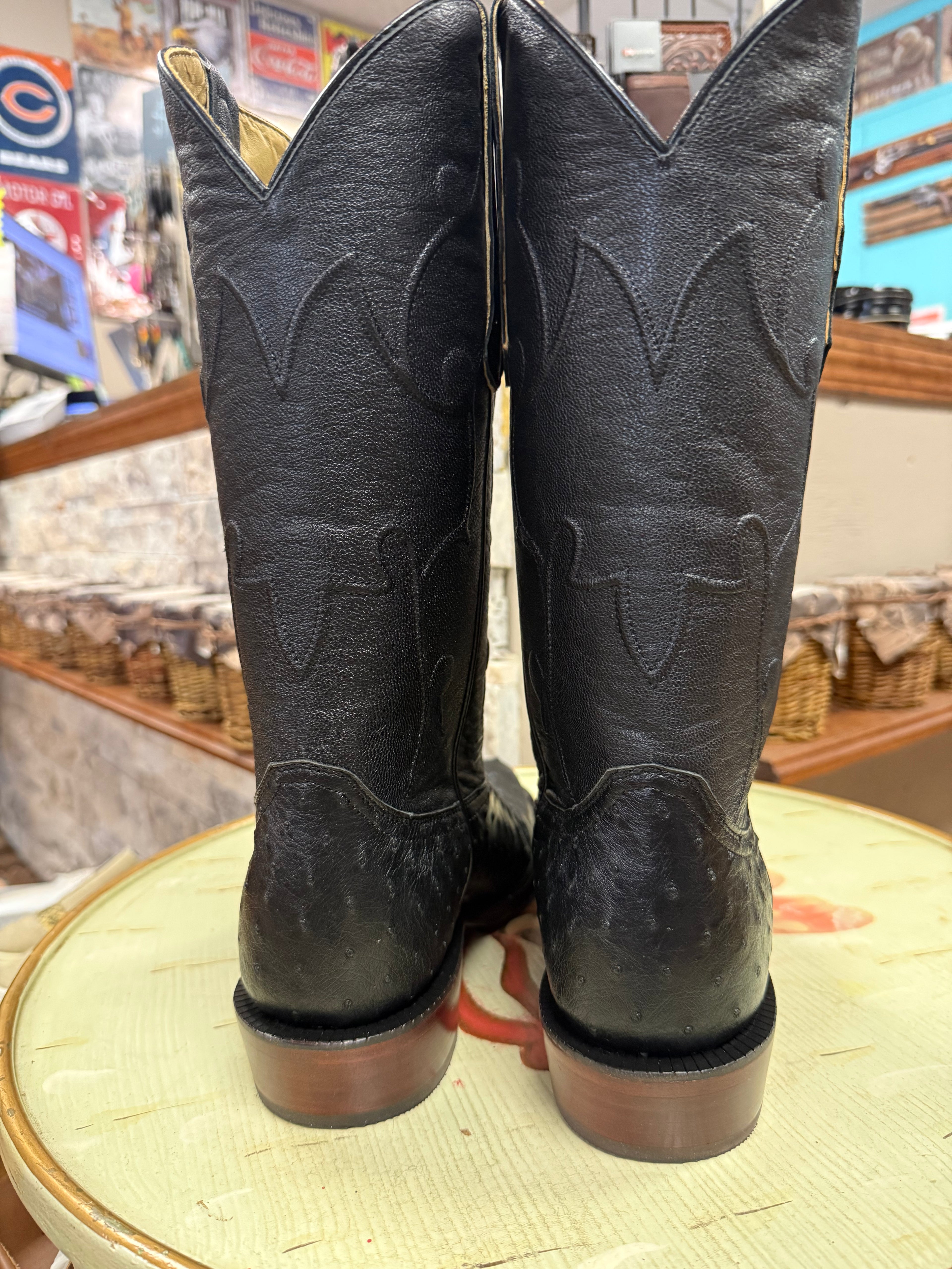 Pair of black cowboy boots on a round surface with a store interior background