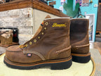 Brown leather boots with 'Thorogood' branding on a wooden surface.