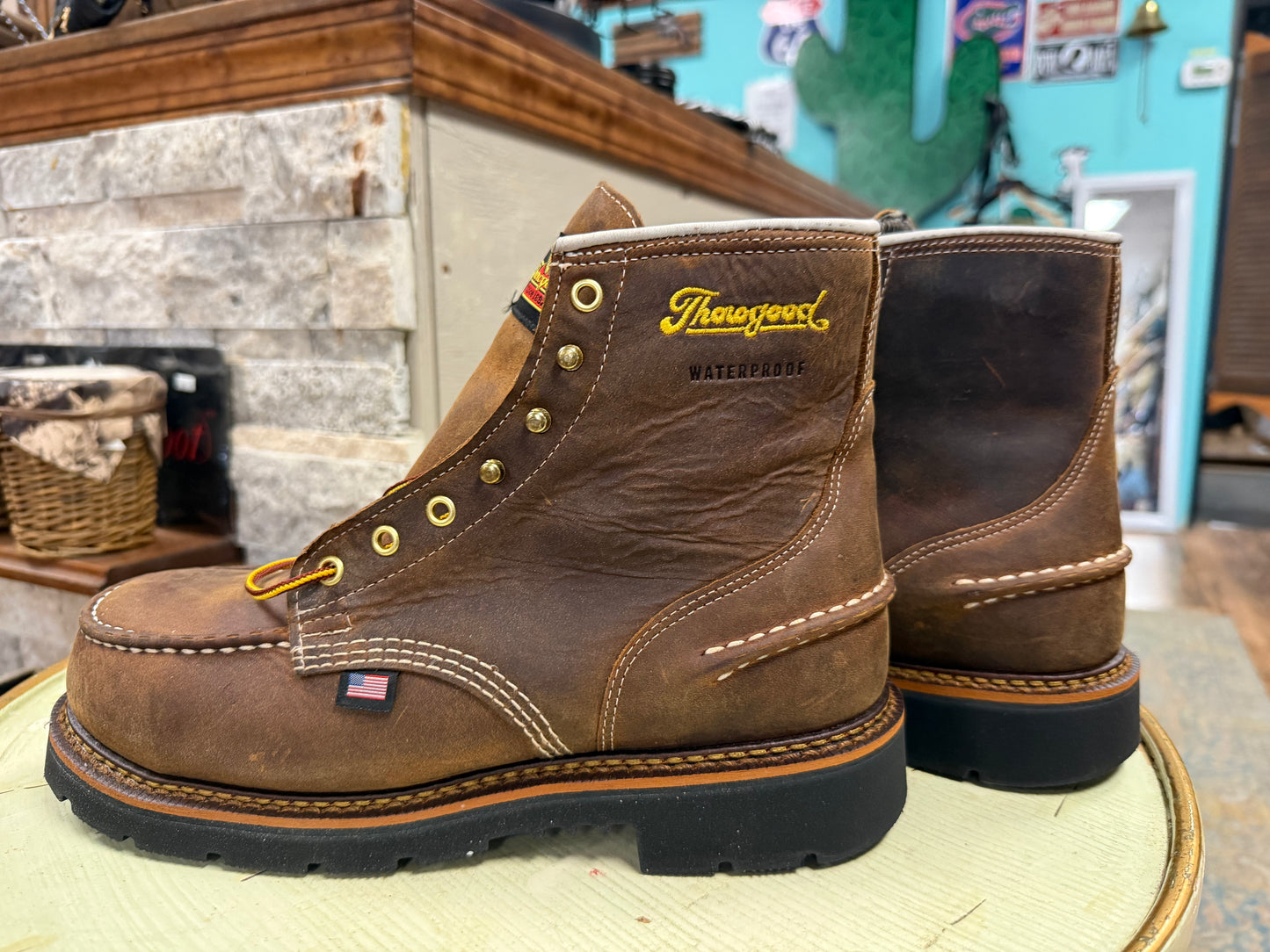 Brown leather boots with 'Thorogood' branding on a wooden surface.