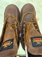 Pair of brown leather shoes with yellow stitching on a light background