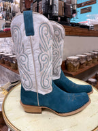 Pair of white and blue cowboy boots on a stool in a store setting.