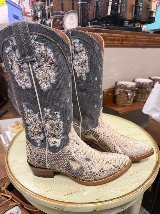 Pair of cowboy boots with snake print on a stool in a store setting
