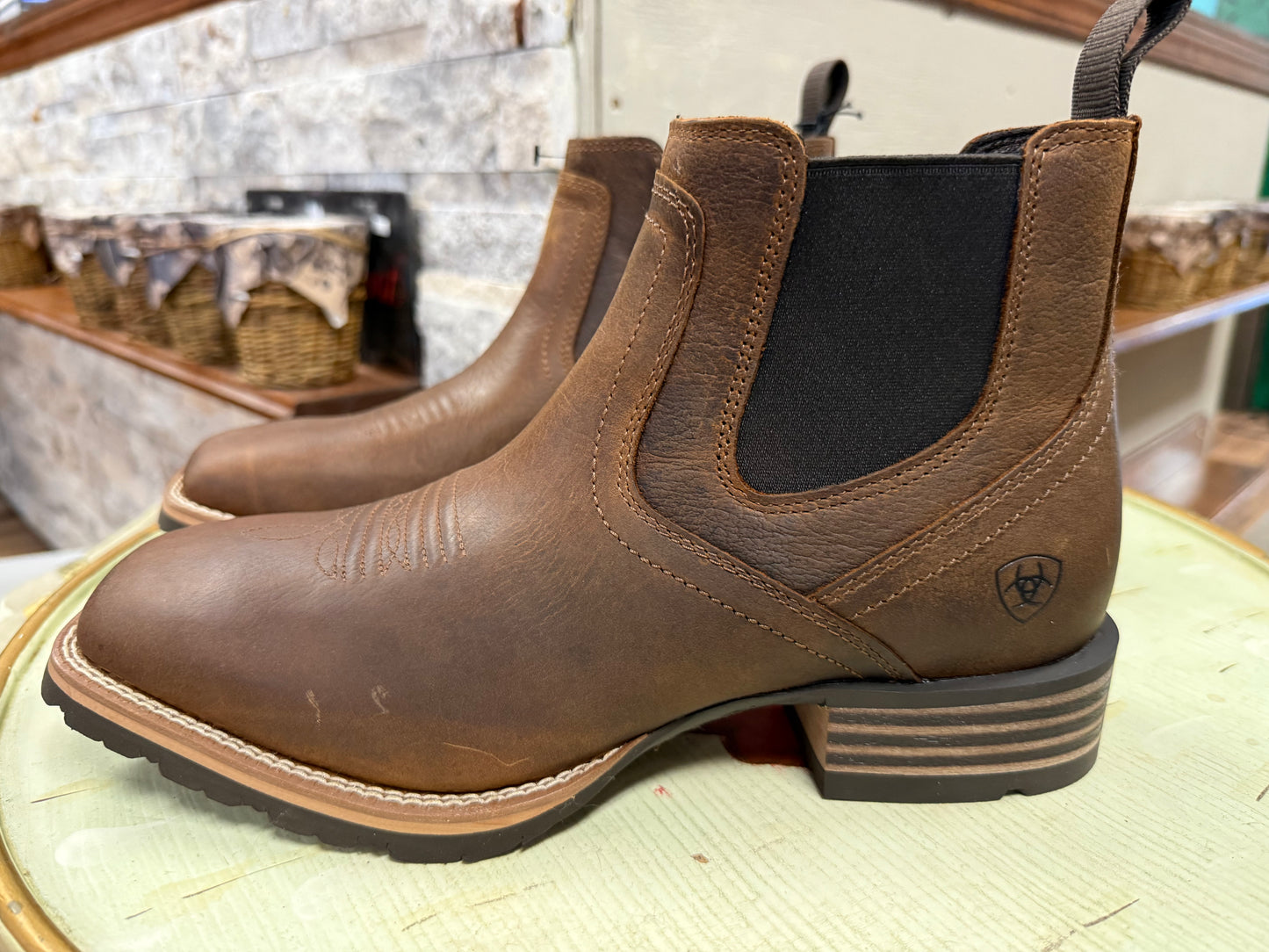 Brown leather boots with a visible brand logo on a textured surface.