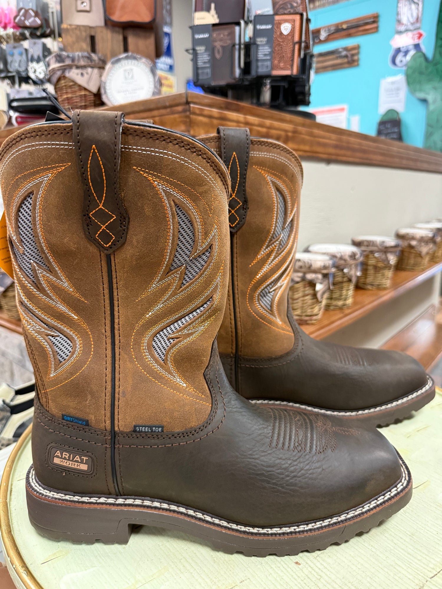 Pair of brown Ariat boots with intricate designs on a store shelf.