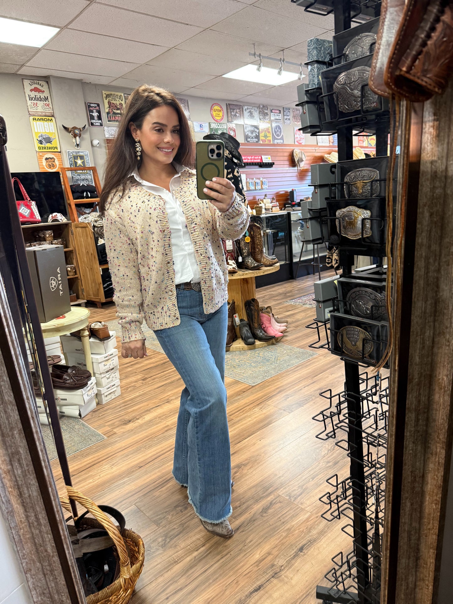 Woman taking a mirror selfie in a store with various items on display.