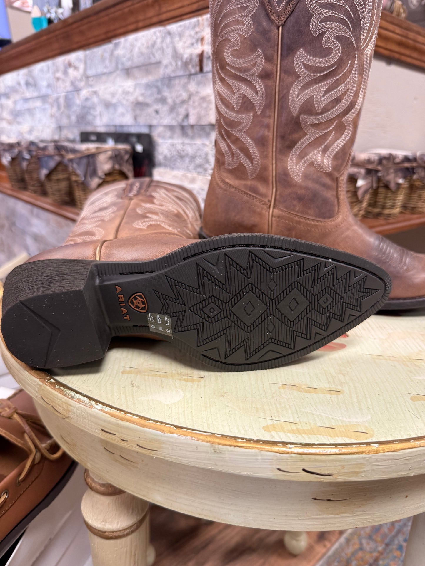 Brown cowboy boot with intricate stitching on a wooden stool.
