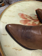 Brown leather boot on a textured surface with floral design
