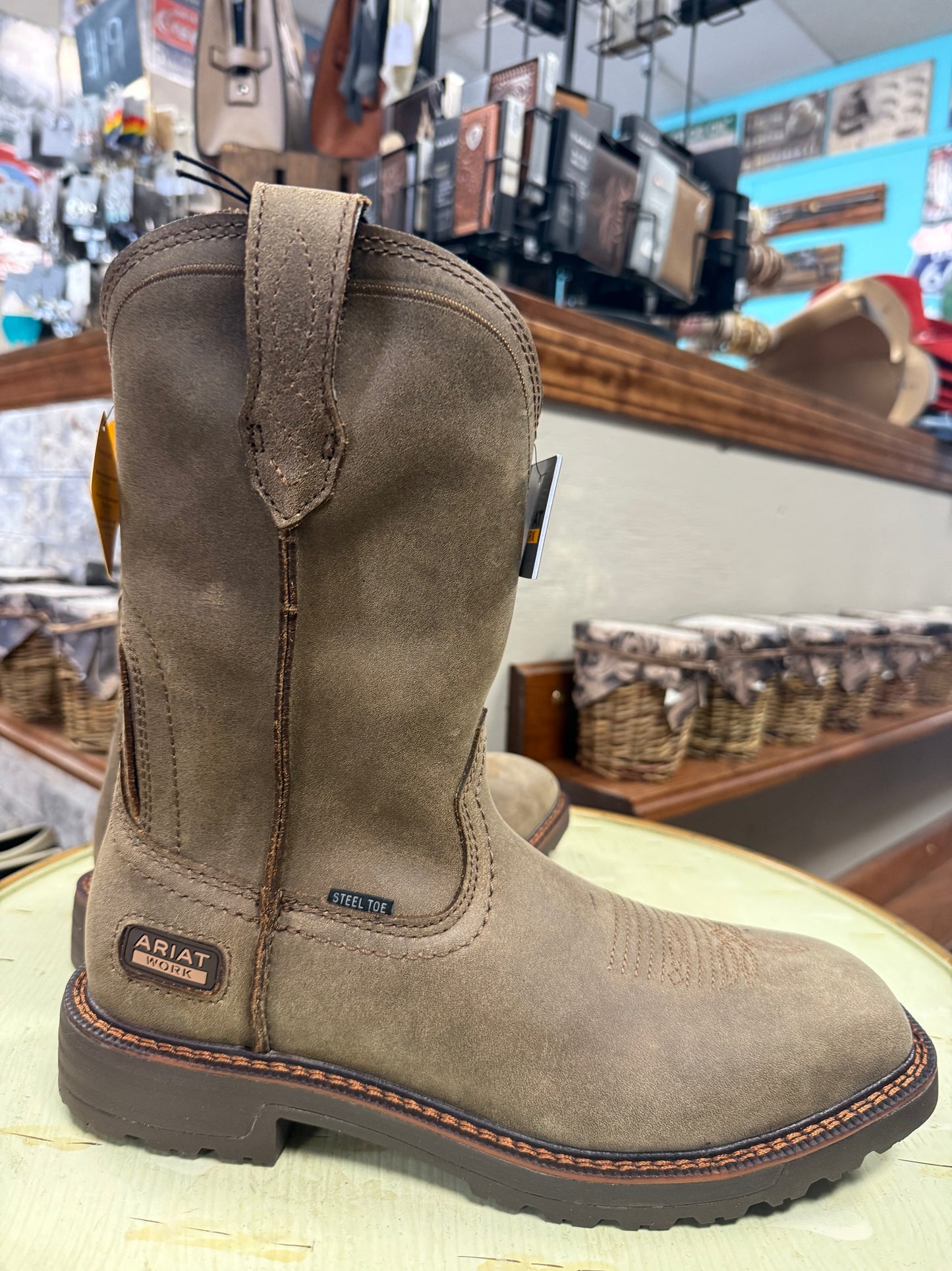 Brown leather boot with Ariat logo on a circular surface in a store setting