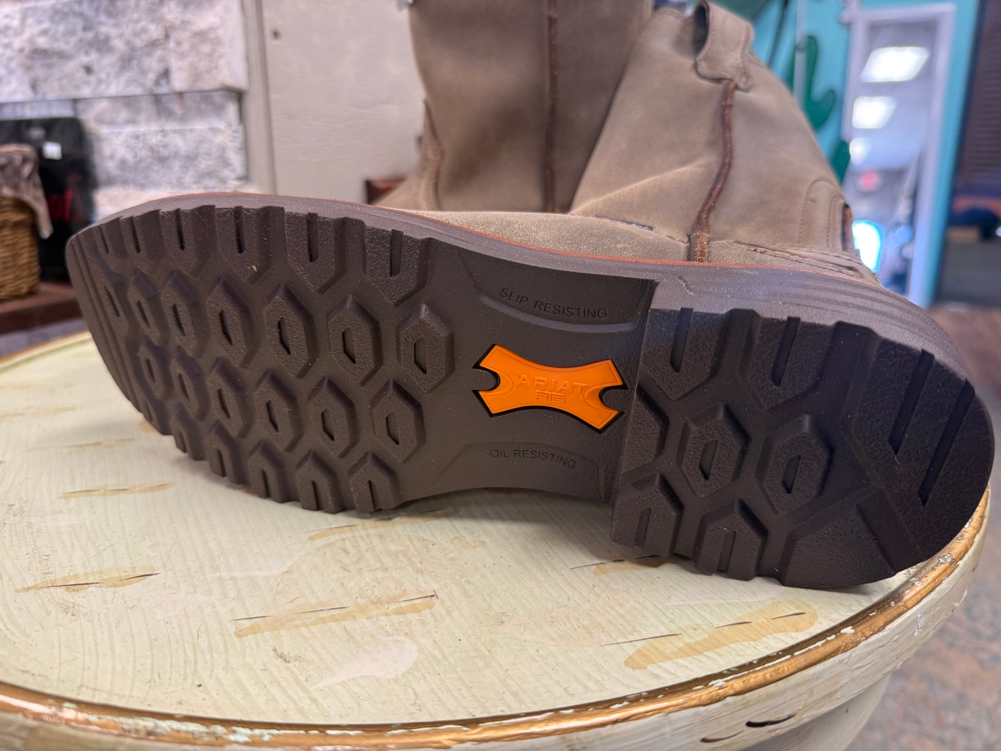 Close-up of a brown boot sole with a visible brand logo on a textured surface.