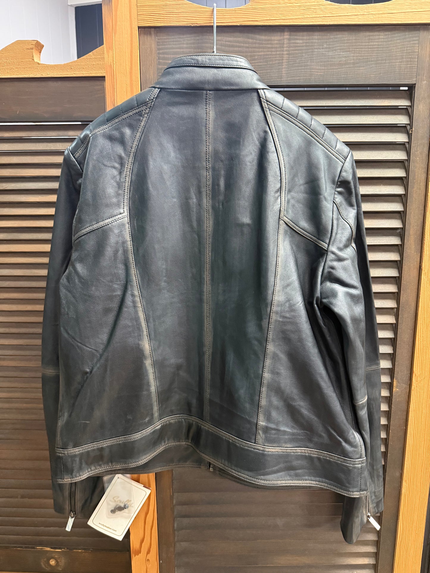 Black leather jacket on a hanger against a wooden panel background