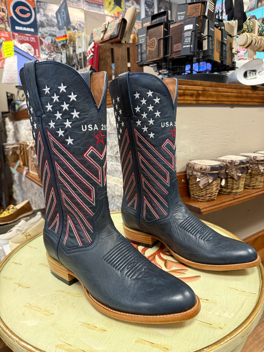 Pair of navy blue cowboy boots with American flag design on a round surface in a store setting.