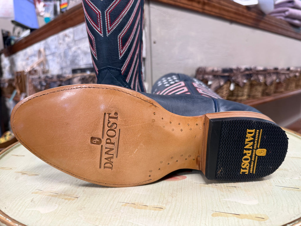 Close-up of a boot with 'Dan Post' branding on a wooden surface.