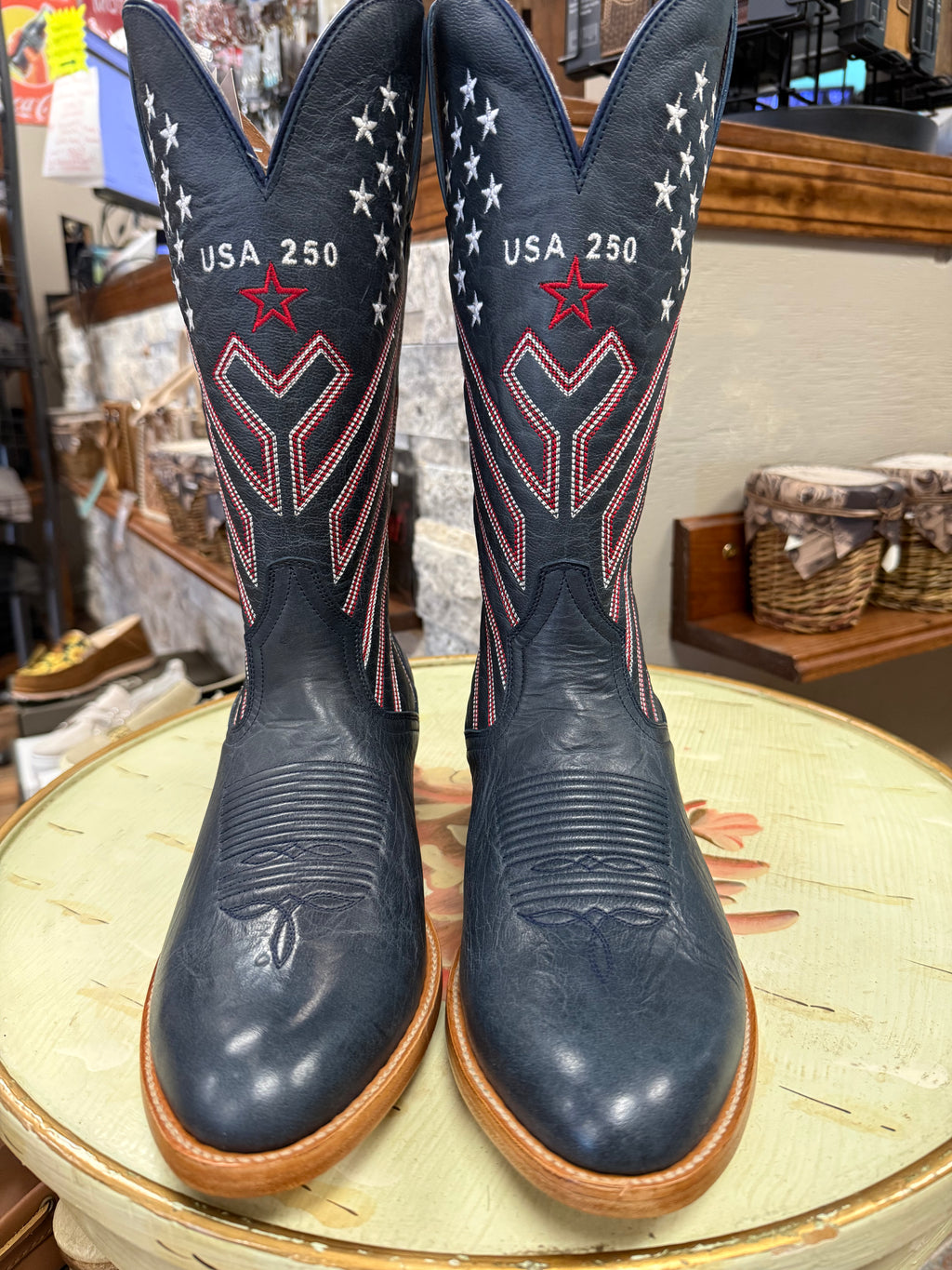 Pair of navy blue cowboy boots with red and white star patterns on a round table.