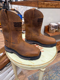 Pair of brown leather boots with black soles on a round wooden stool.