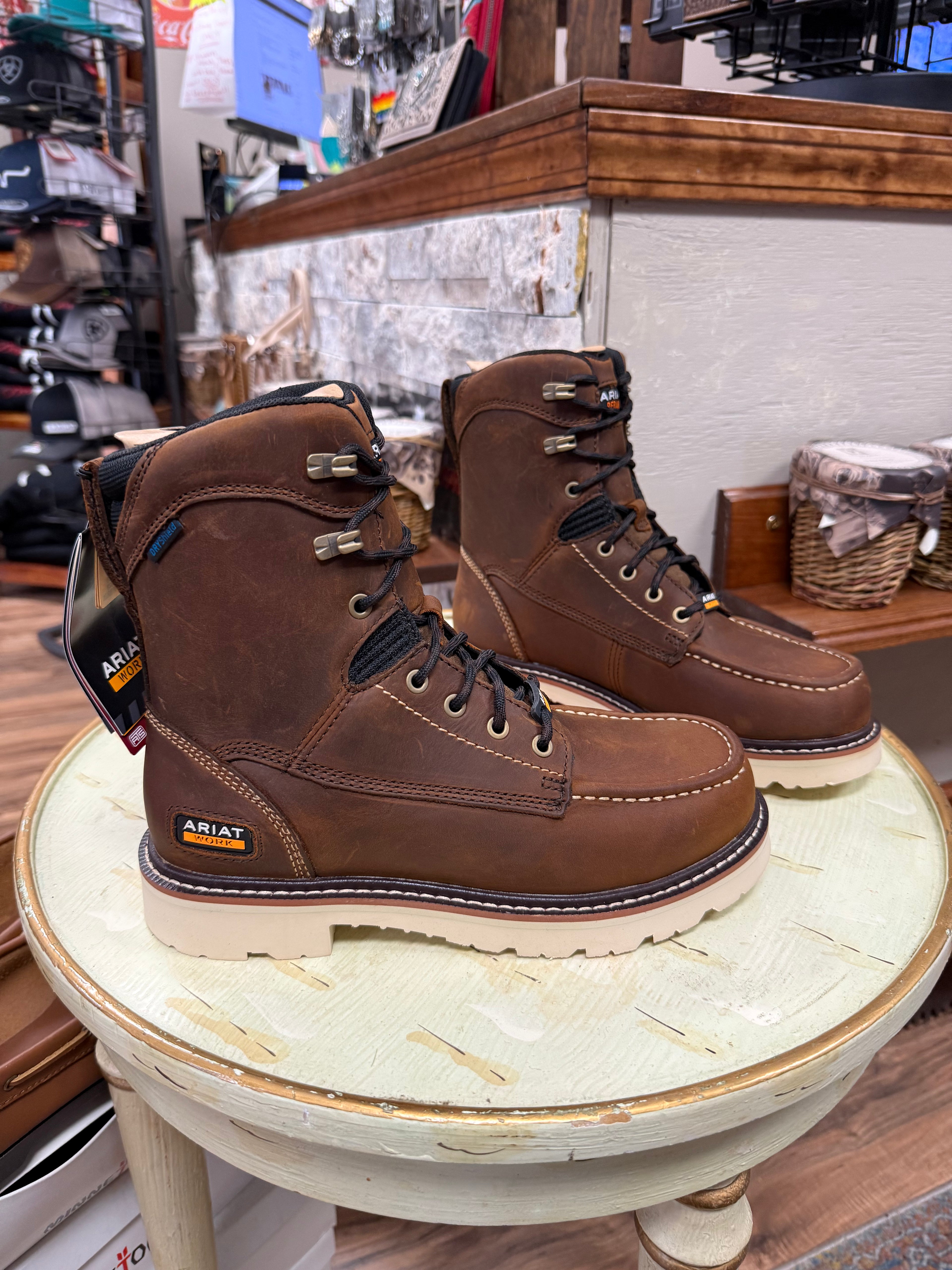 Pair of brown Ariat boots on a wooden stool in a store setting