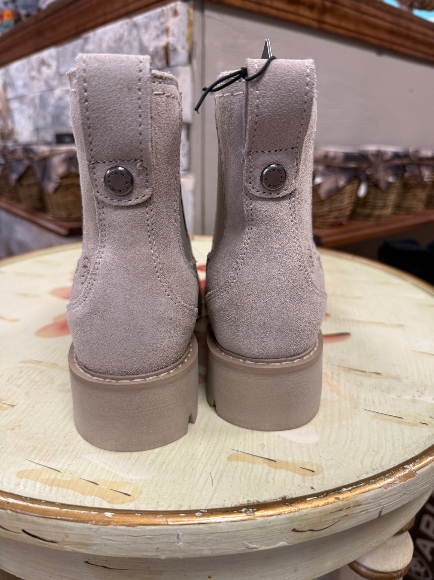 Pair of gray suede boots on a round table with a blurred background