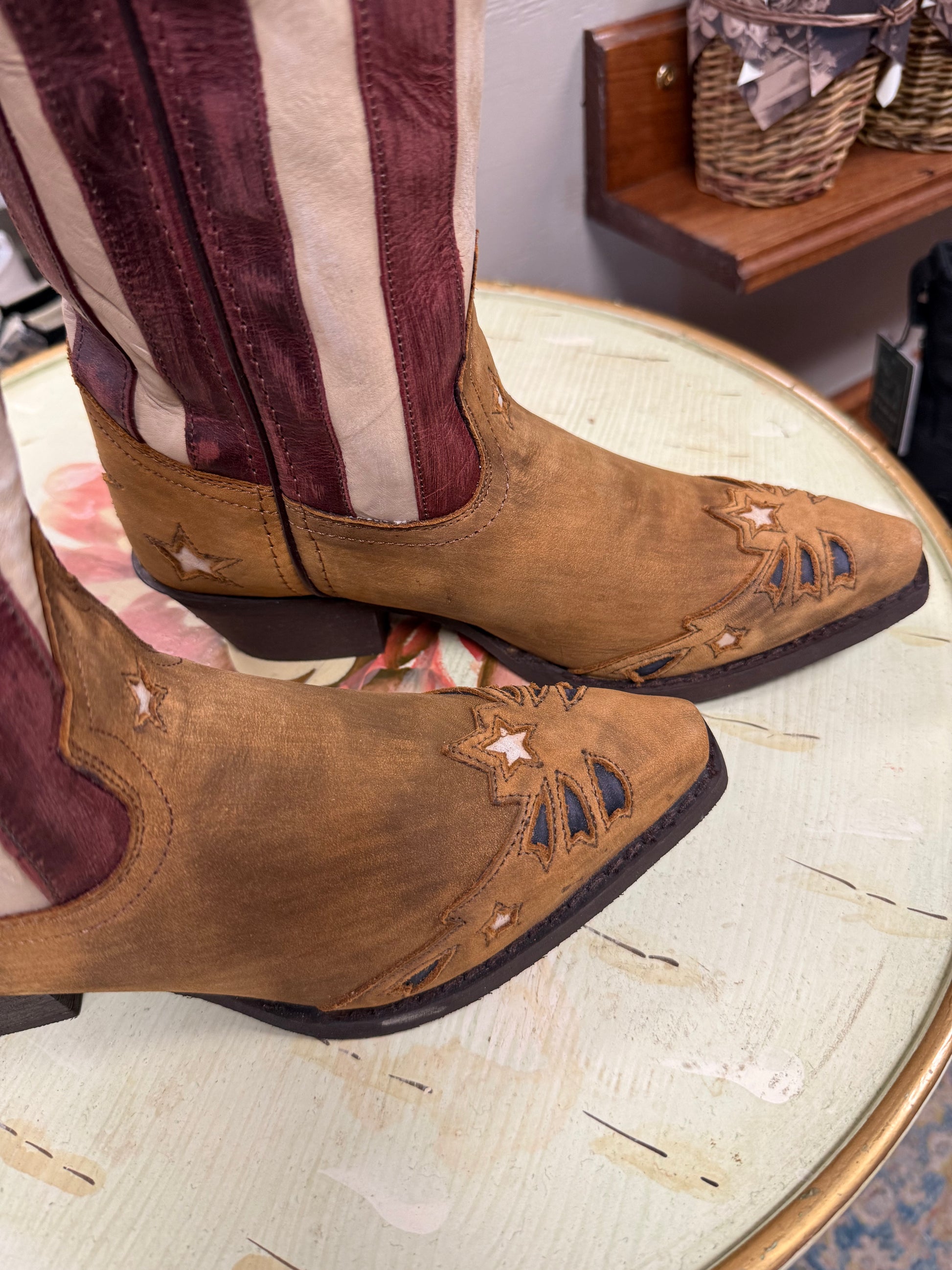 Brown cowboy boots with star designs on a glass table