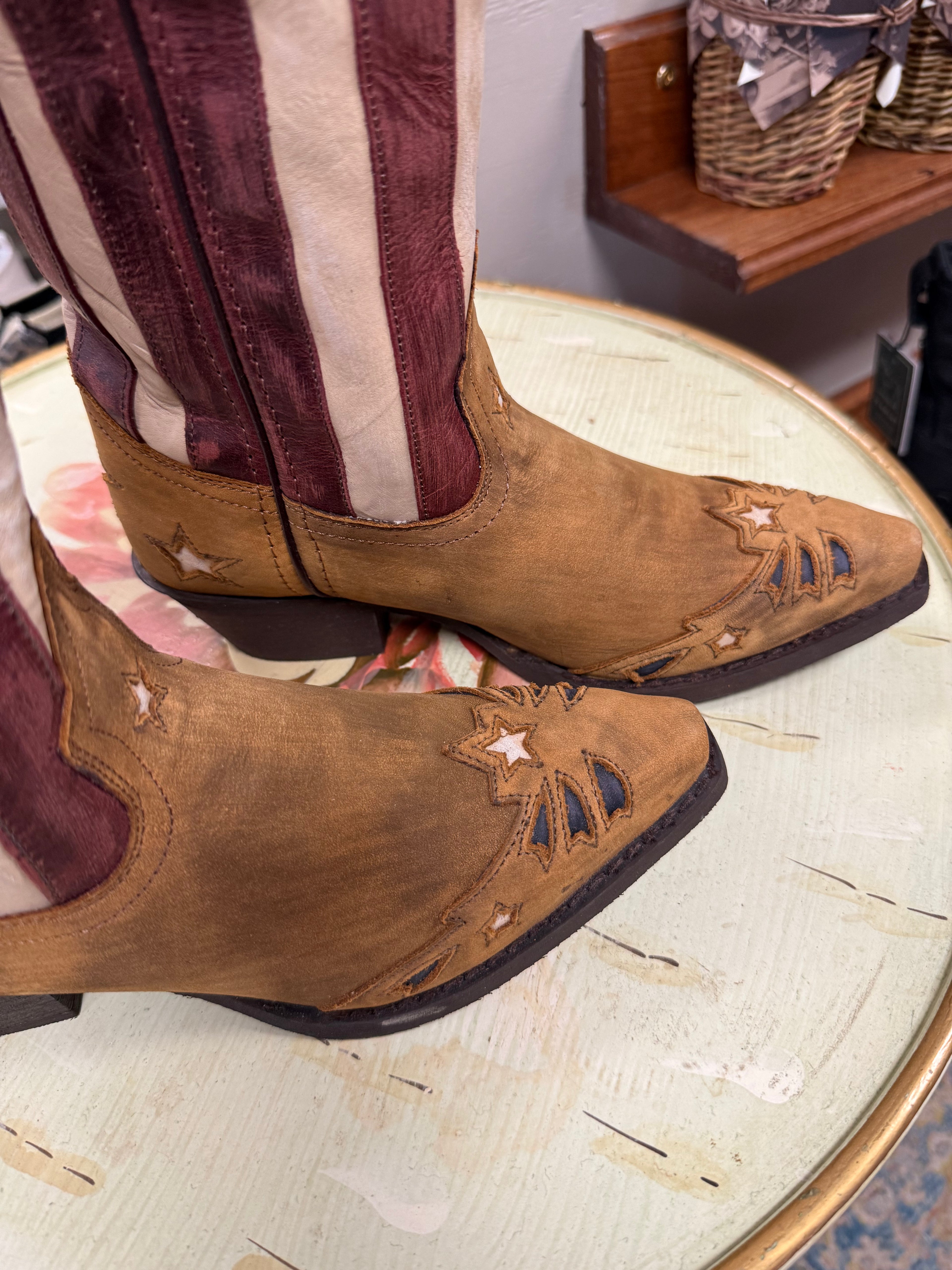 Brown cowboy boots with star designs on a glass table