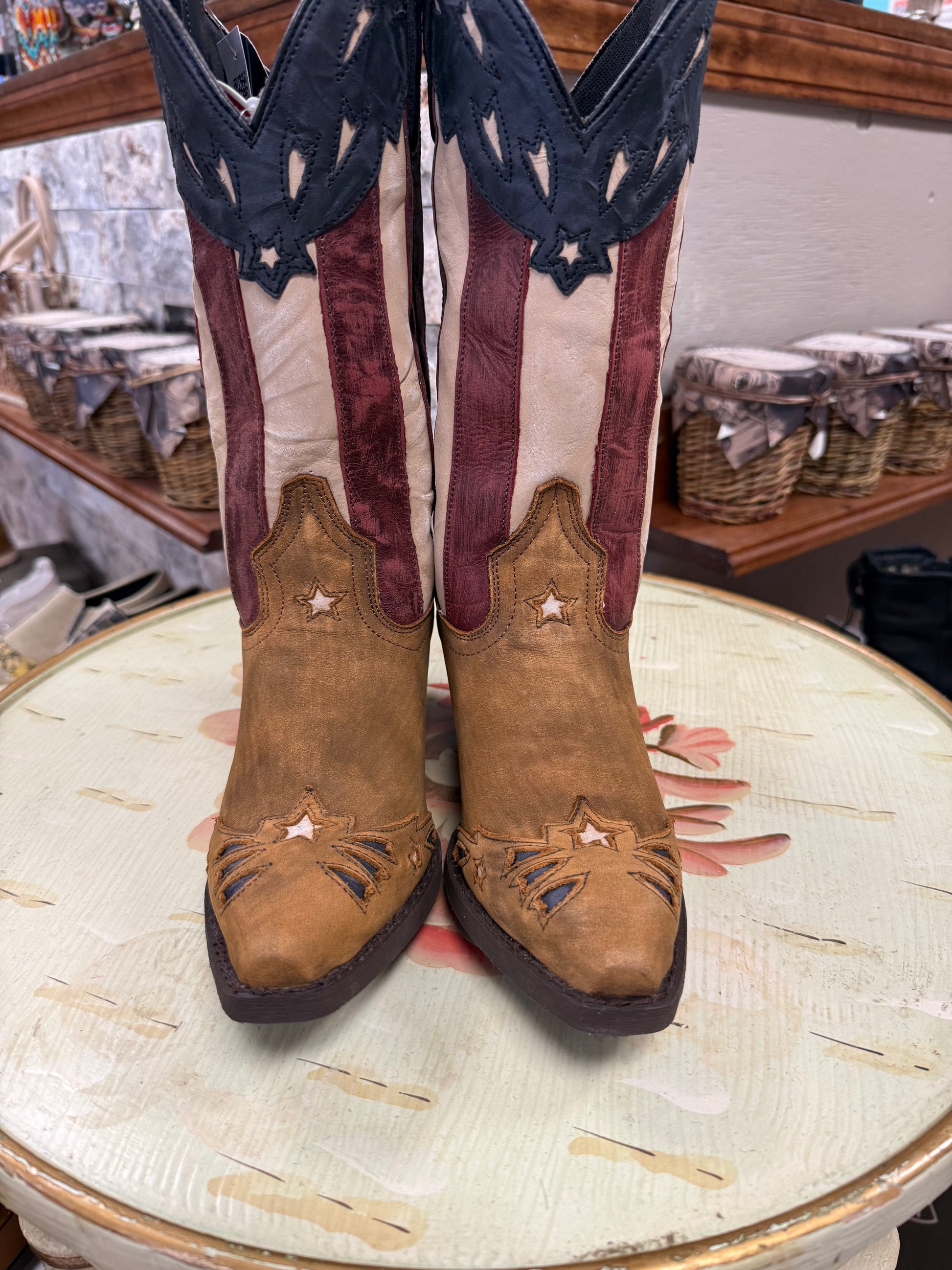 Pair of brown cowboy boots with American flag design on a round table.