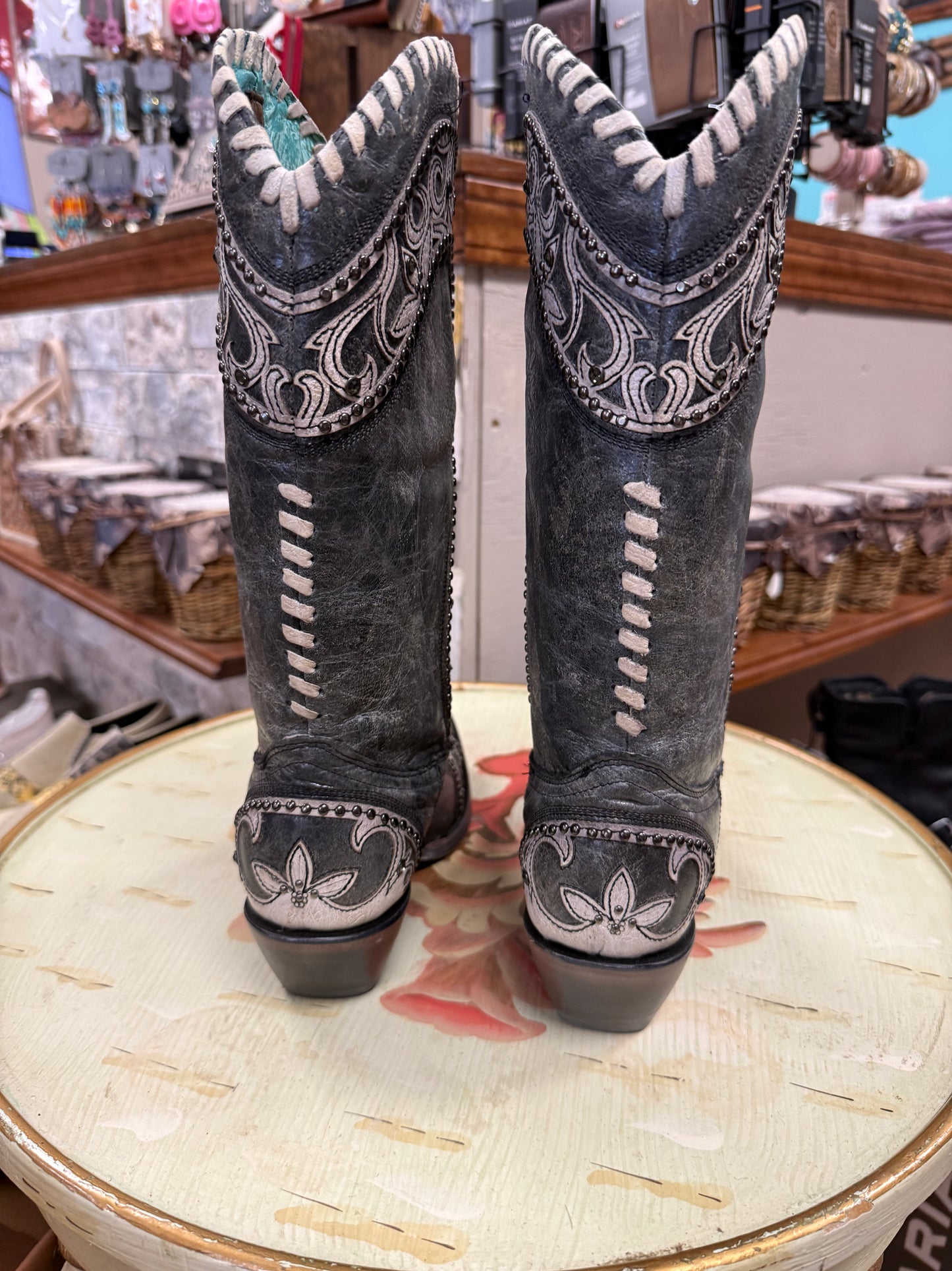 Pair of gray cowboy boots with white stitching on a decorative surface.