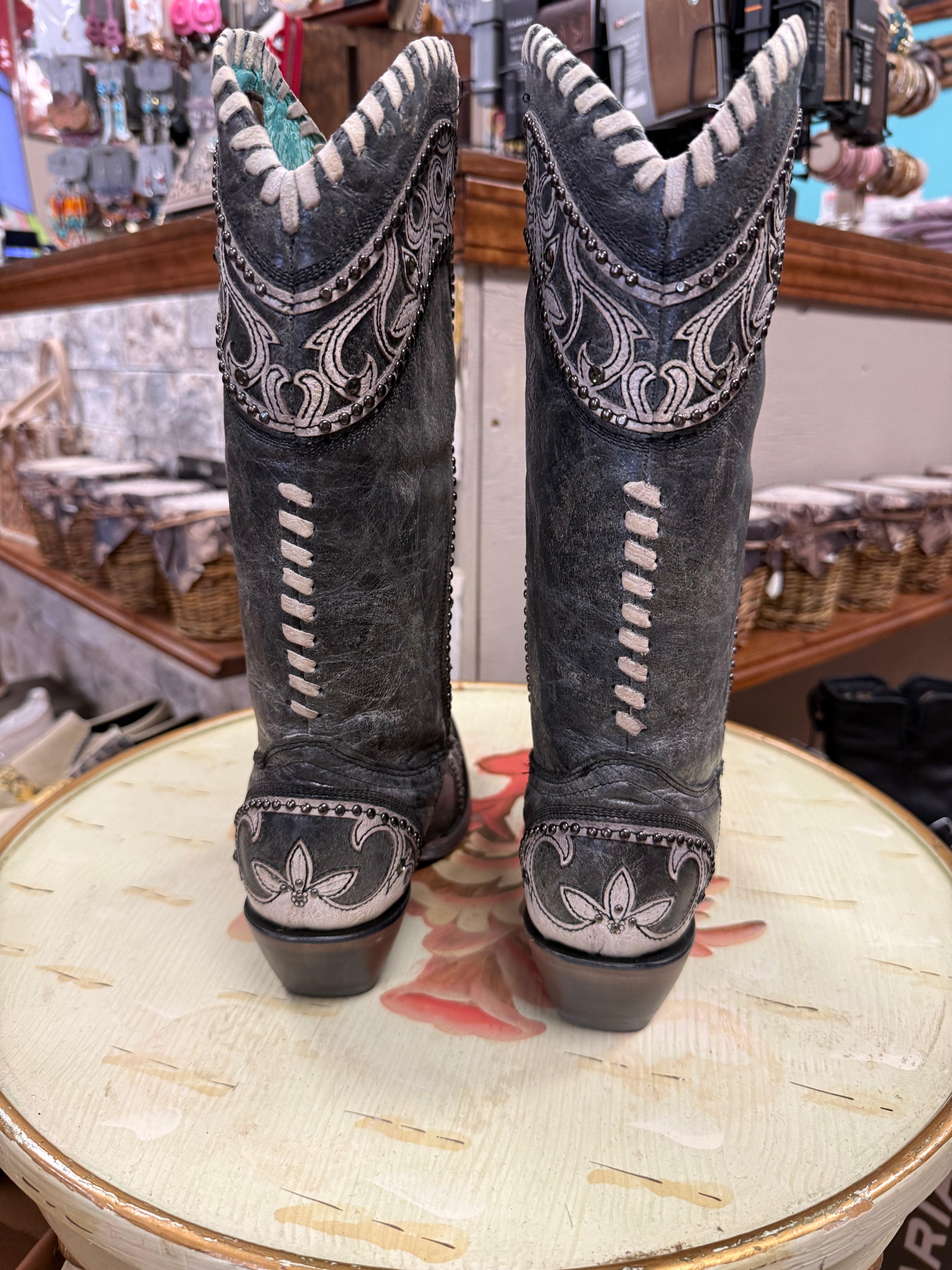 Pair of gray cowboy boots with white stitching on a decorative surface.