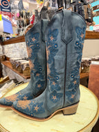 Blue embroidered cowboy boots on a circular surface with a store interior background.