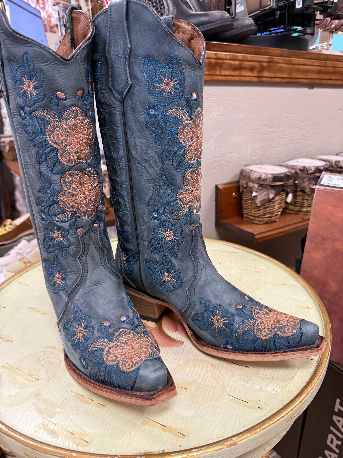 Blue embroidered cowboy boots on a round table with a store interior background