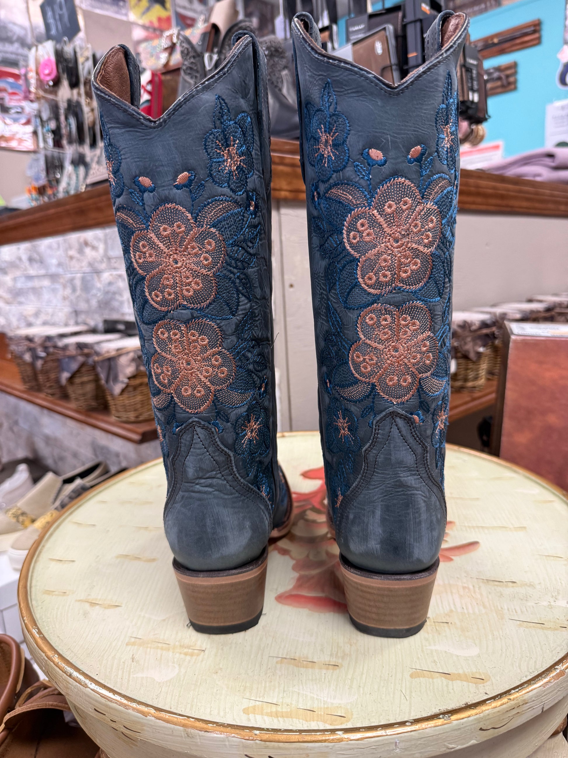 Blue embroidered cowboy boots on a round table with a store interior background