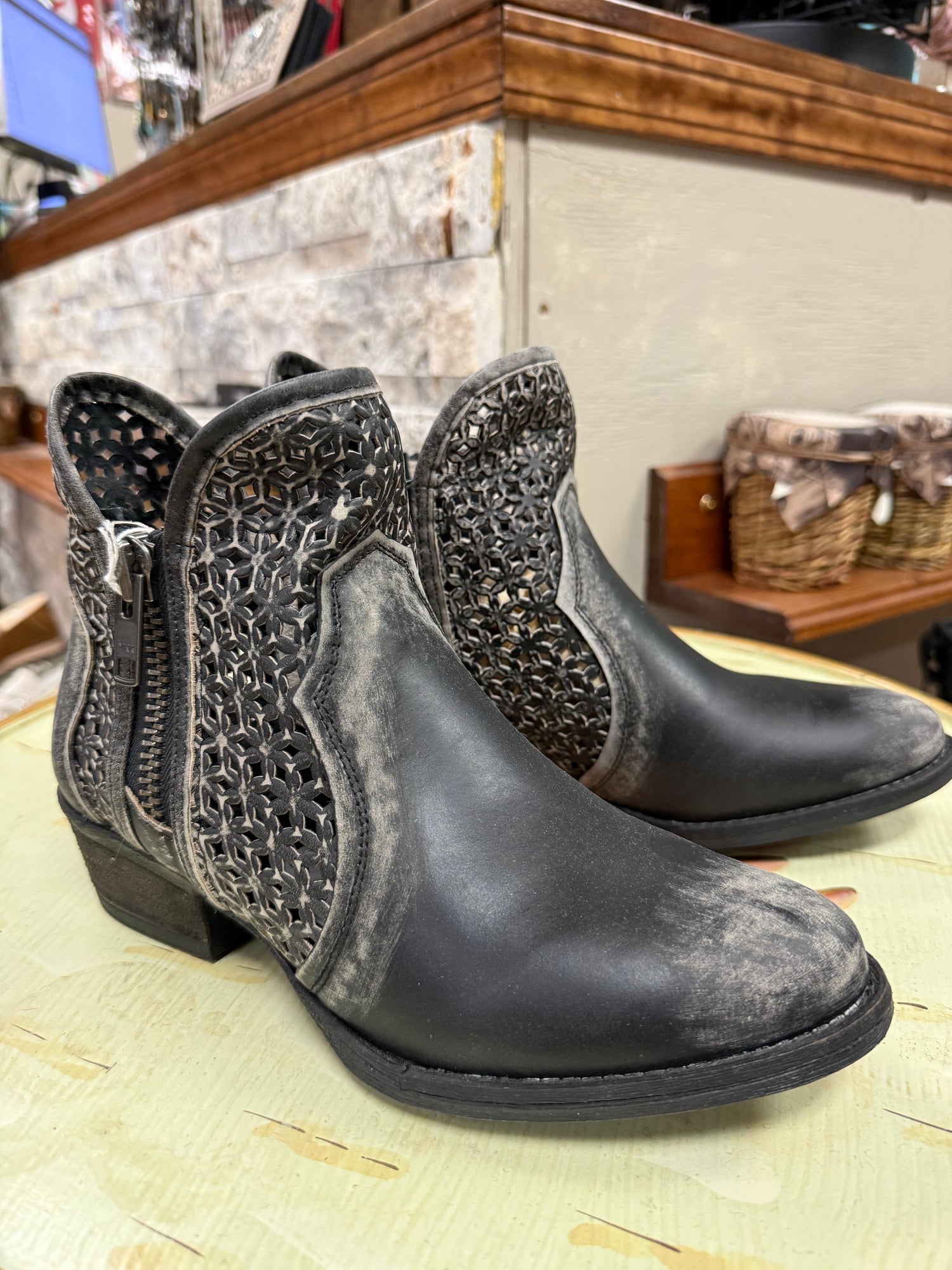 Pair of black ankle boots with decorative patterns on a woven surface.