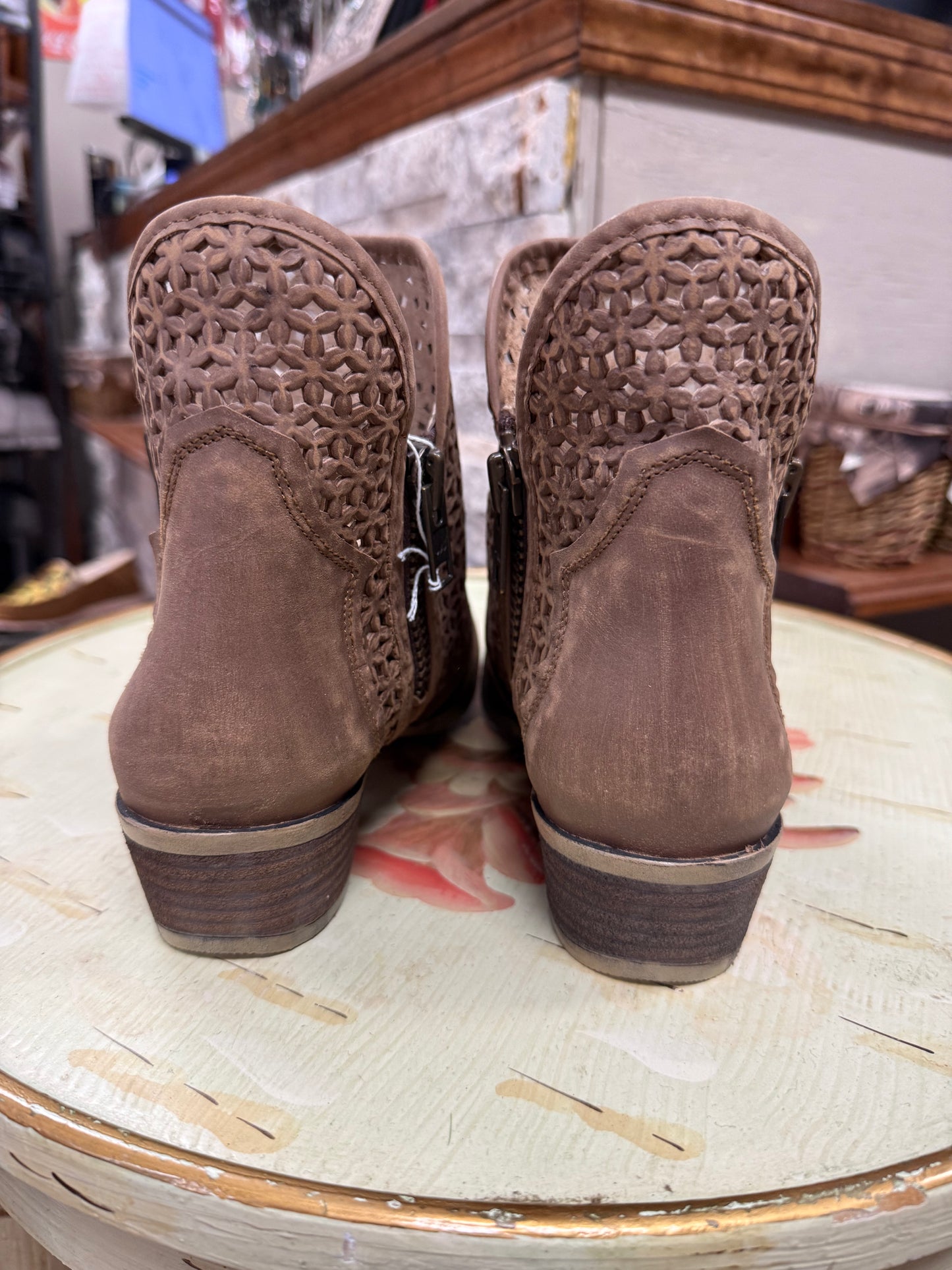Pair of brown suede boots with woven detailing on a round table.