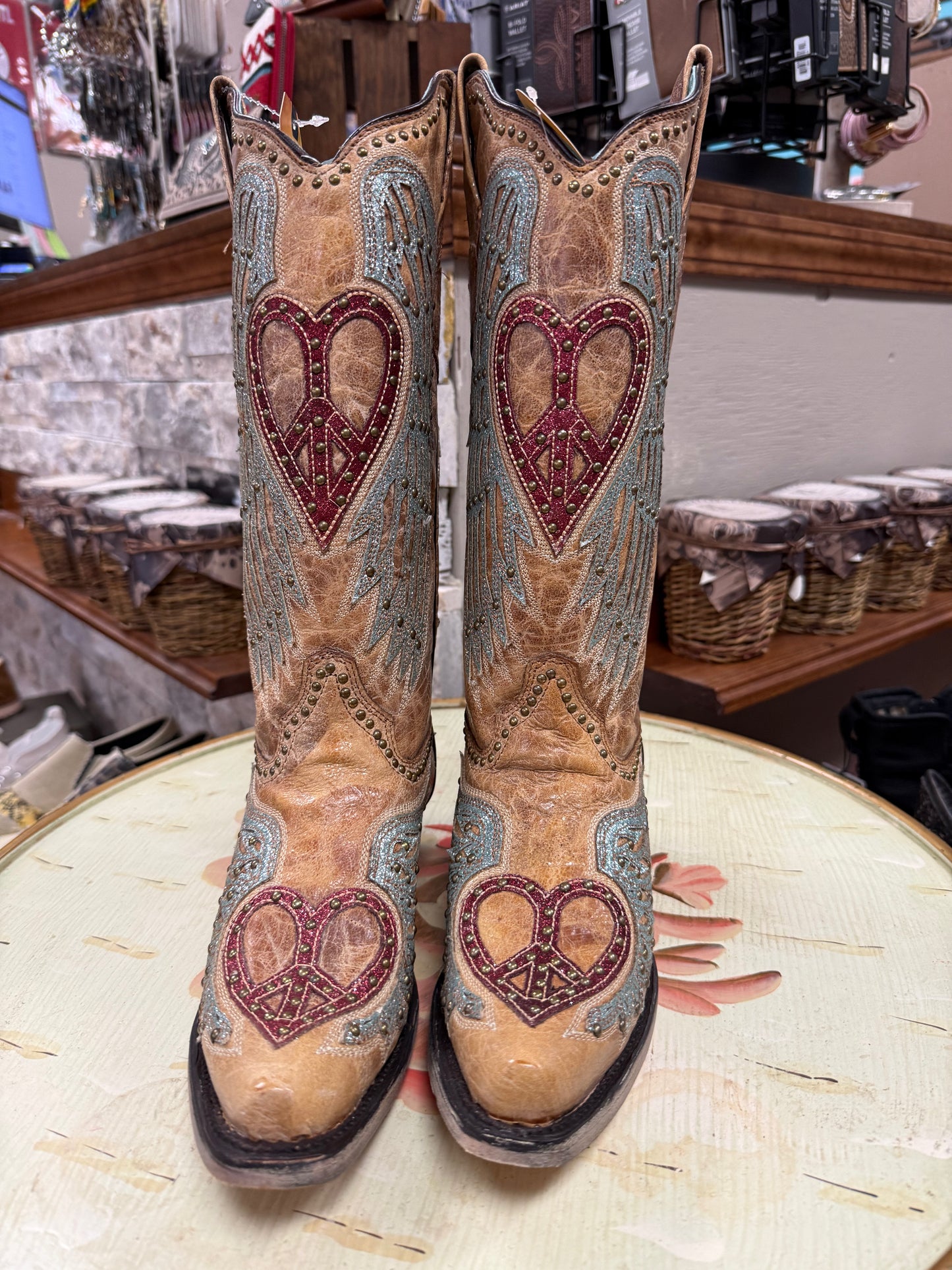 Pair of cowboy boots with heart designs on a round surface.