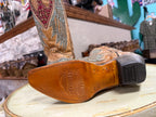 Close-up of a tan cowboy boot with intricate designs on a wooden surface.
