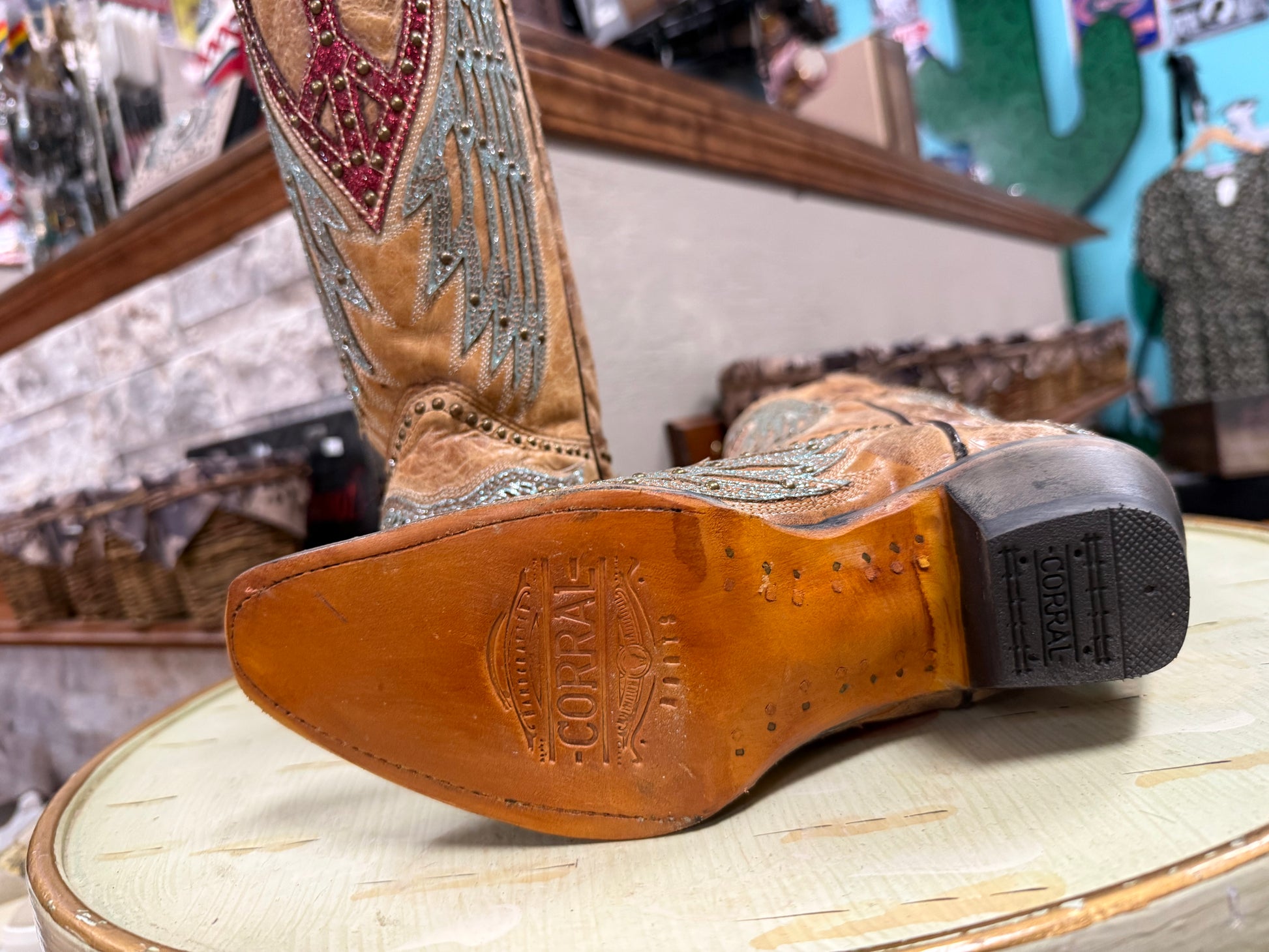 Close-up of a tan cowboy boot with intricate designs on a wooden surface.