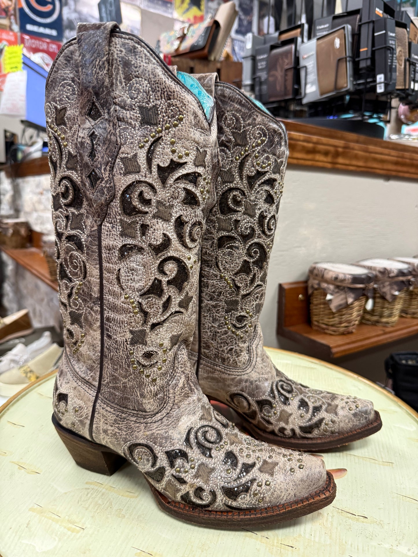 Pair of ornate cowboy boots on a table with a store setting in the background