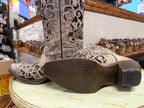 Close-up of a Corral cowboy boot with intricate designs on a light green surface.