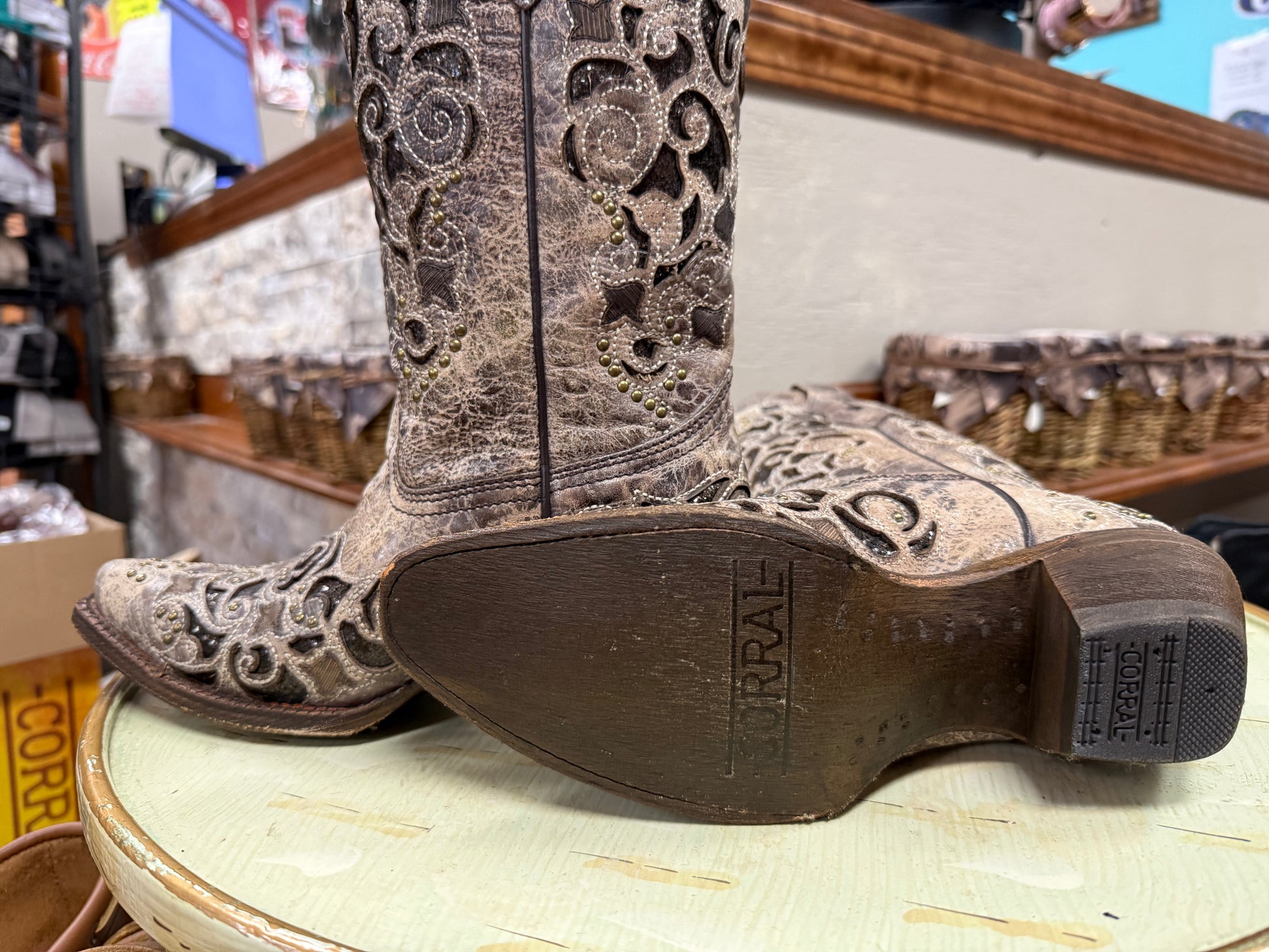 Close-up of a Corral cowboy boot with intricate designs on a light green surface.