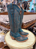 Blue cowboy boots with intricate designs on a round table in a store setting.