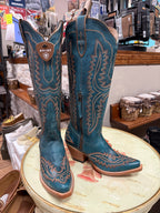 Pair of blue Ariat cowboy boots on a round table in a store setting.