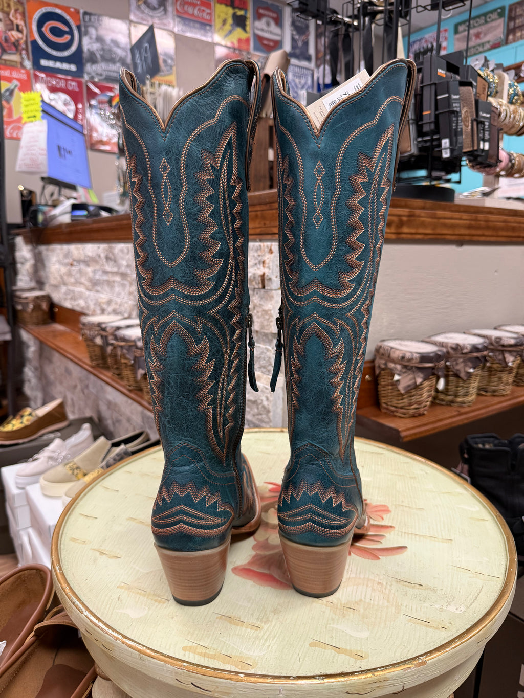 Pair of blue cowboy boots on a round table with a store interior background