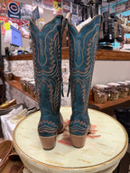 Pair of blue cowboy boots on a round table with a store interior background