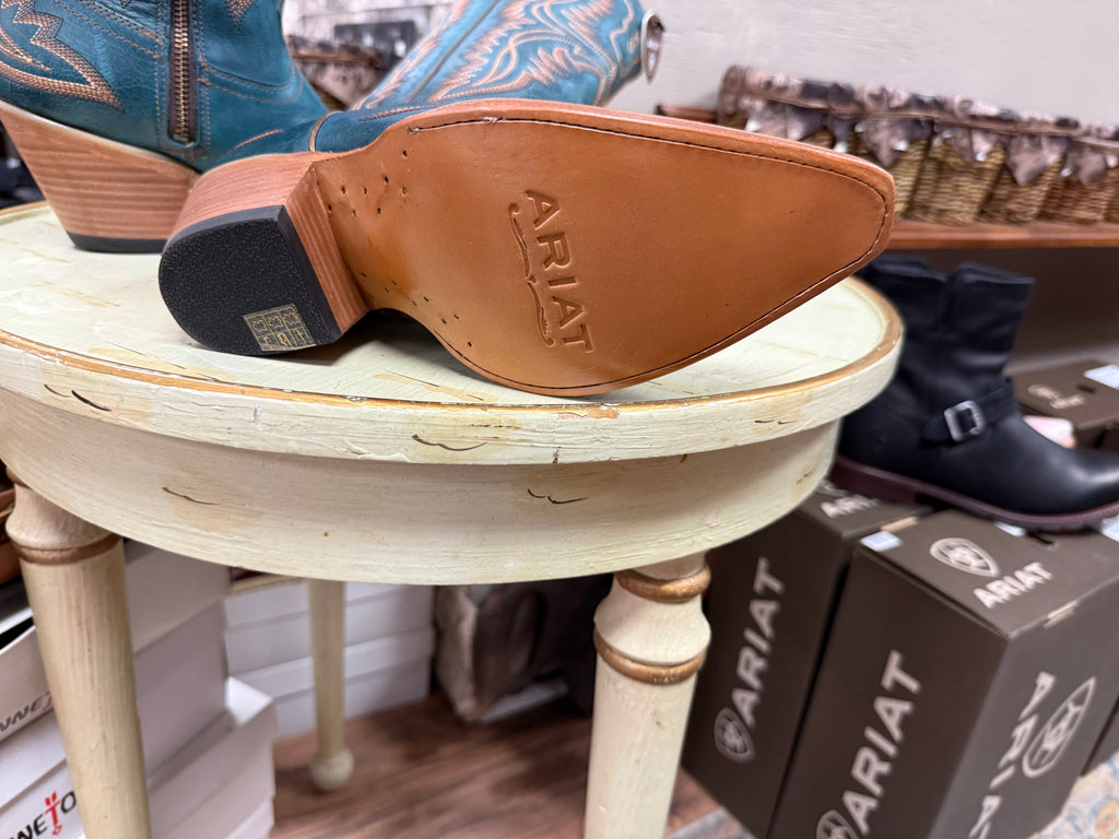 Close-up of Ariat boots on a stool with boxes in the background