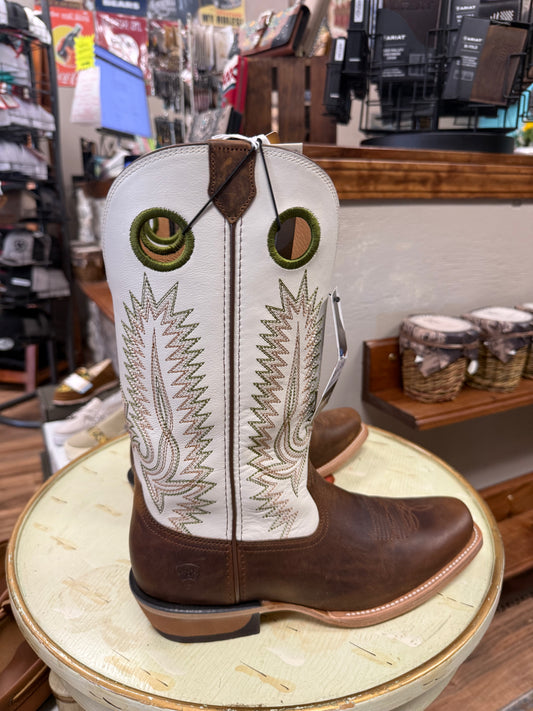 Brown and white cowboy boot with intricate embroidery on a round stool in a store setting.