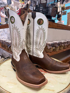 Pair of brown and white cowboy boots with intricate designs on a round surface in a store setting.