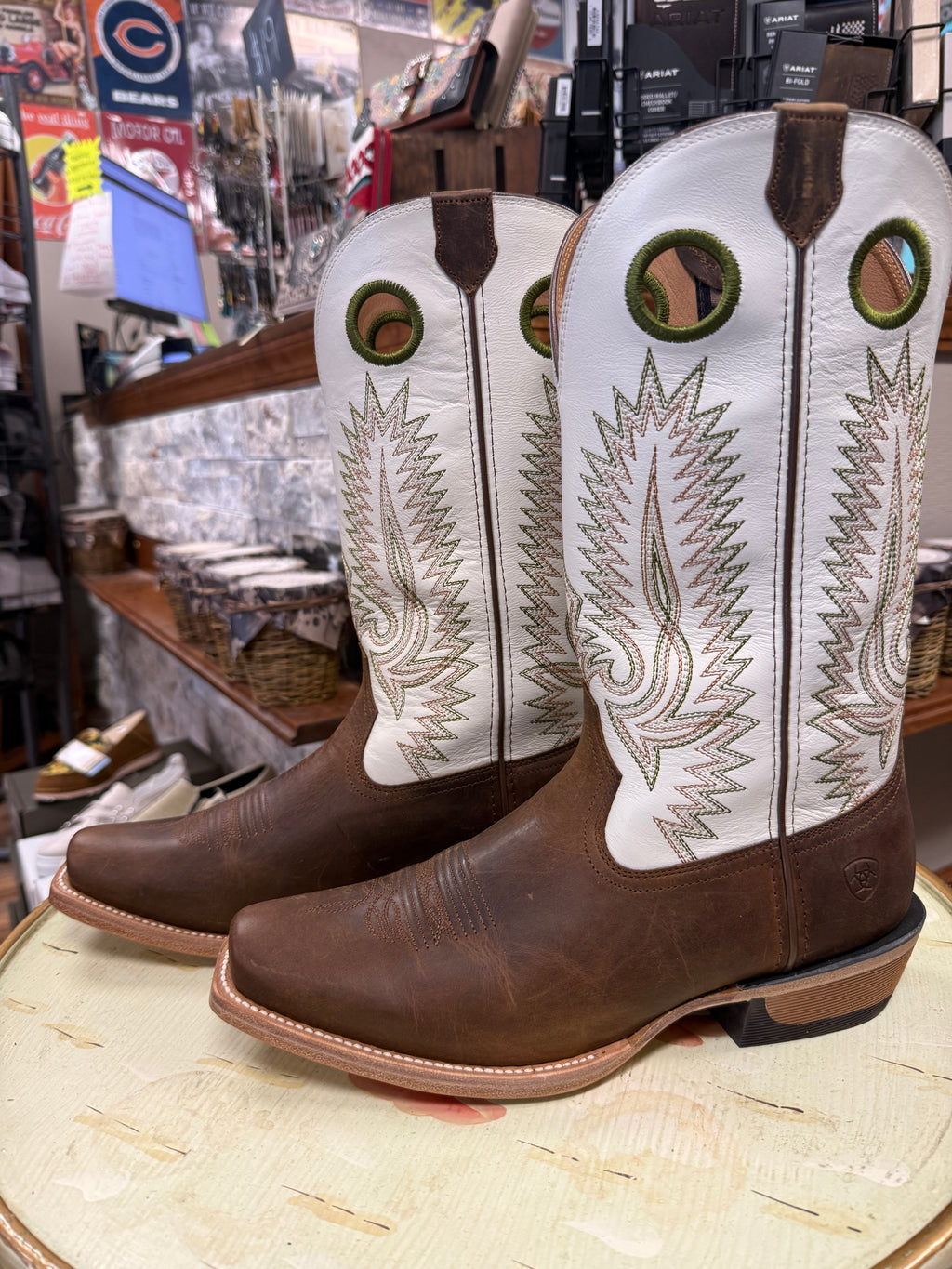 Pair of brown and white cowboy boots with intricate designs on a round surface.