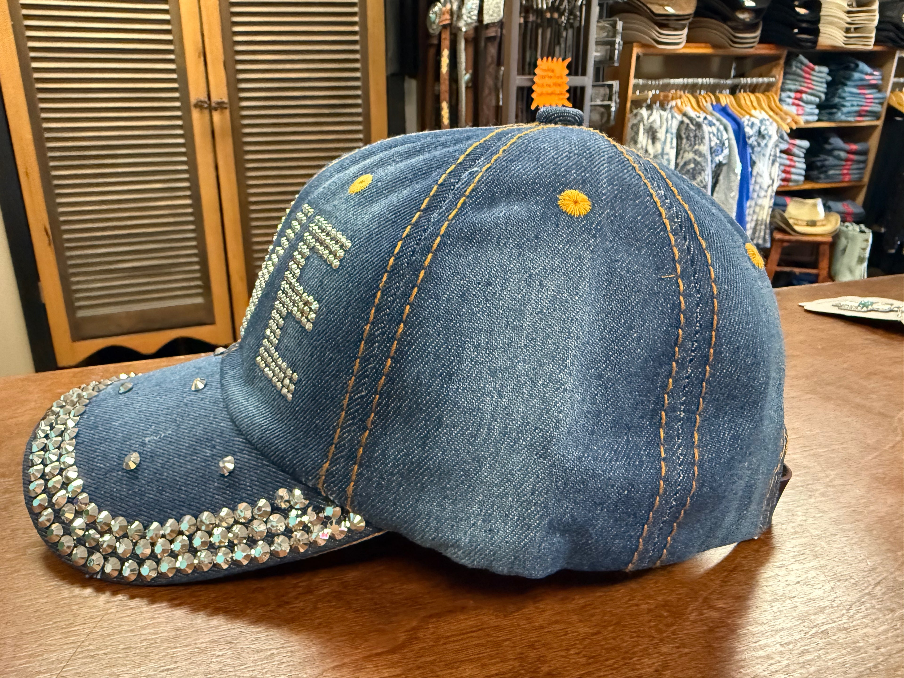 Denim cap with rhinestone embellishments on a wooden surface