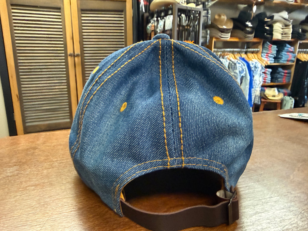 Blue denim cap with yellow stitching on a wooden surface in a store setting