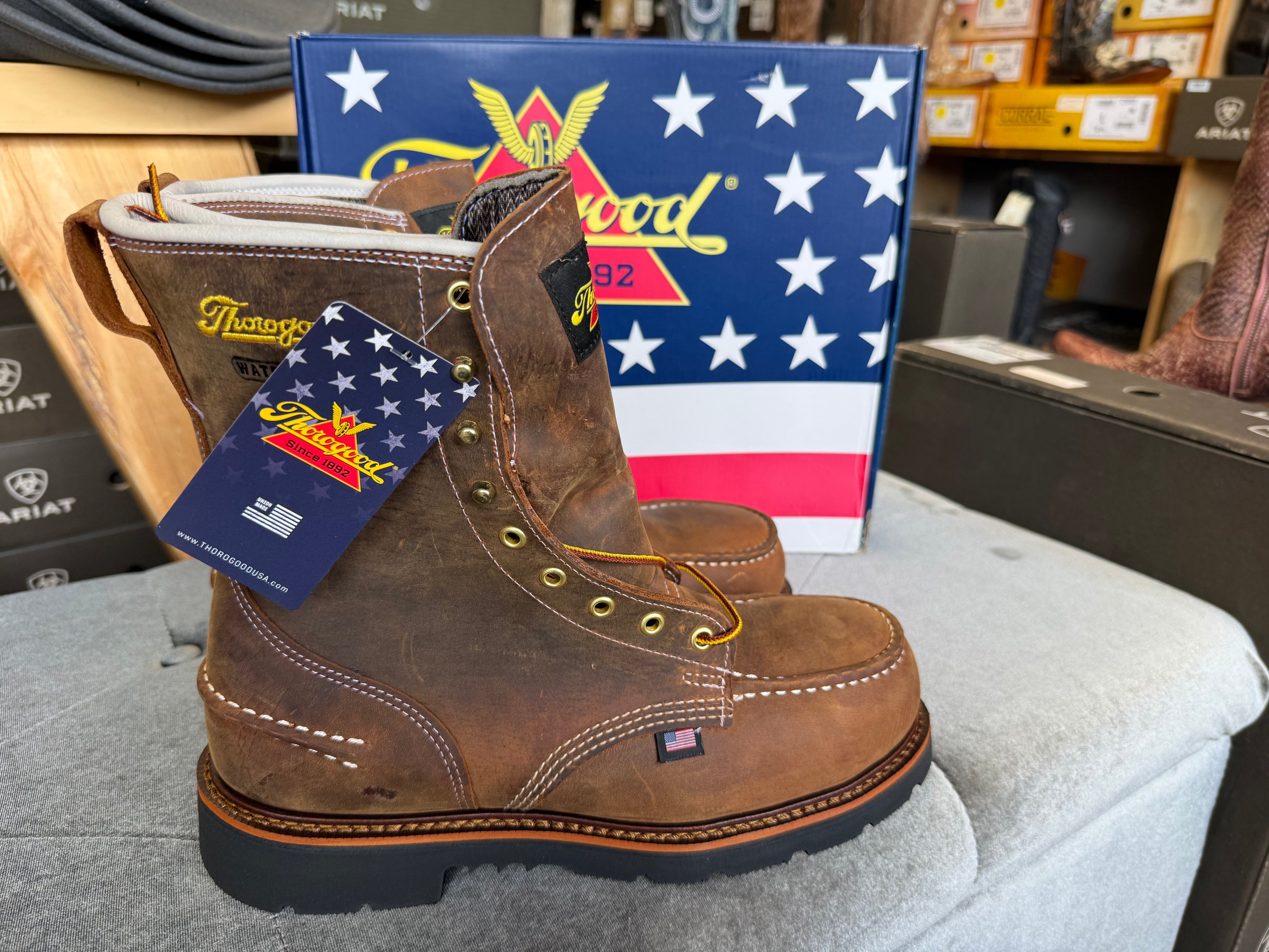 Brown work boots with a tag in front of a Patriotic American flag display.